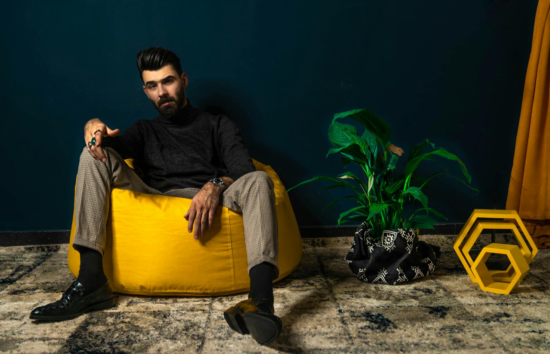 Brodaty mężczyzna siedzi na żółtej pufie sako w nowoczesnym salonie