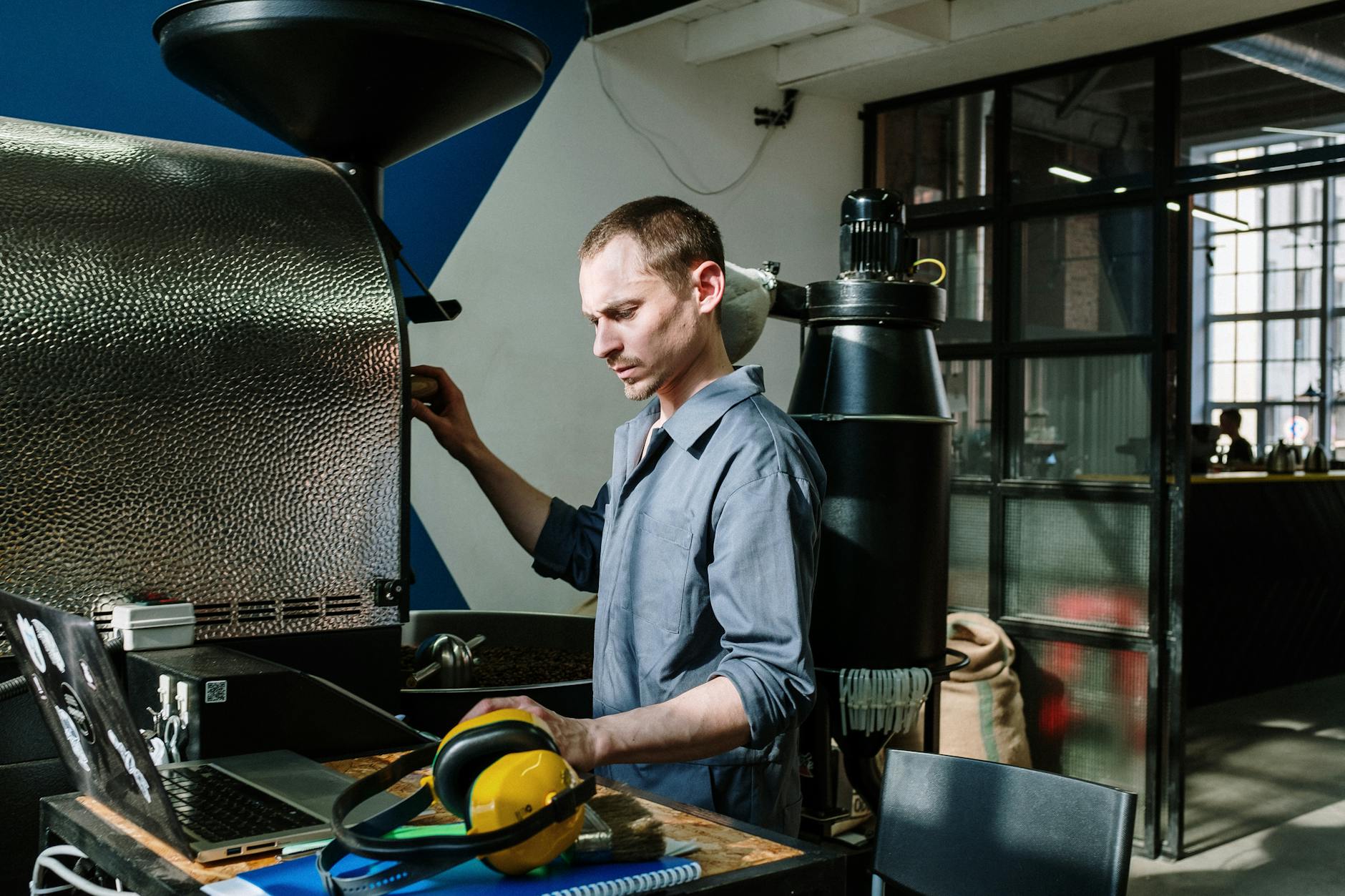 Mężczyzna obsługuje piec do palenia kawy w warsztacie industrialnym