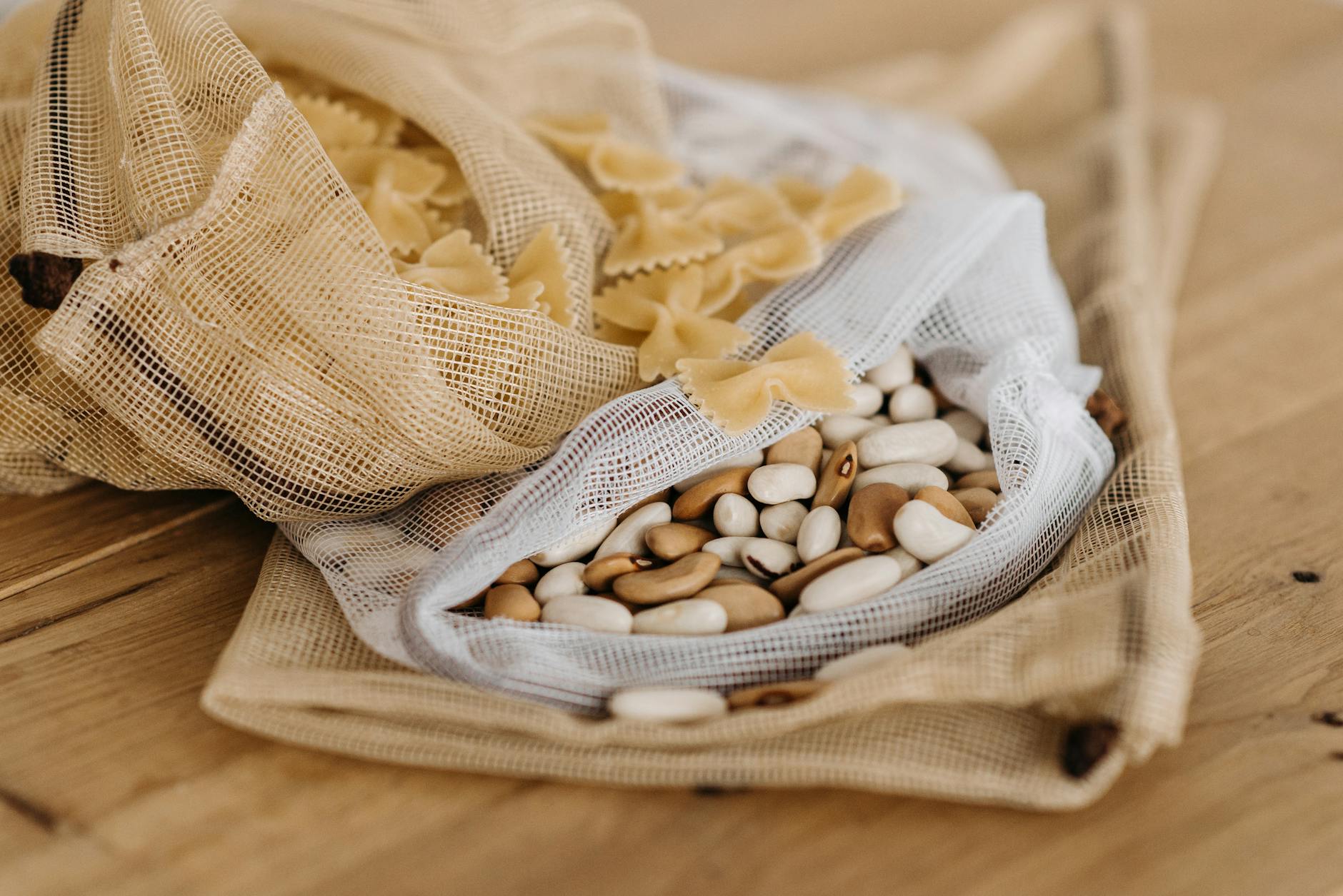 Tkaninowe woreczki z makaronem kokardki i mieszanką fasoli na drewnie