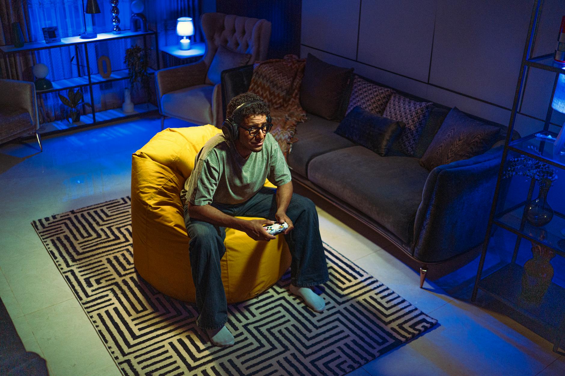 Mężczyzna w średnim wieku gra na konsoli w salonie z pufą sako