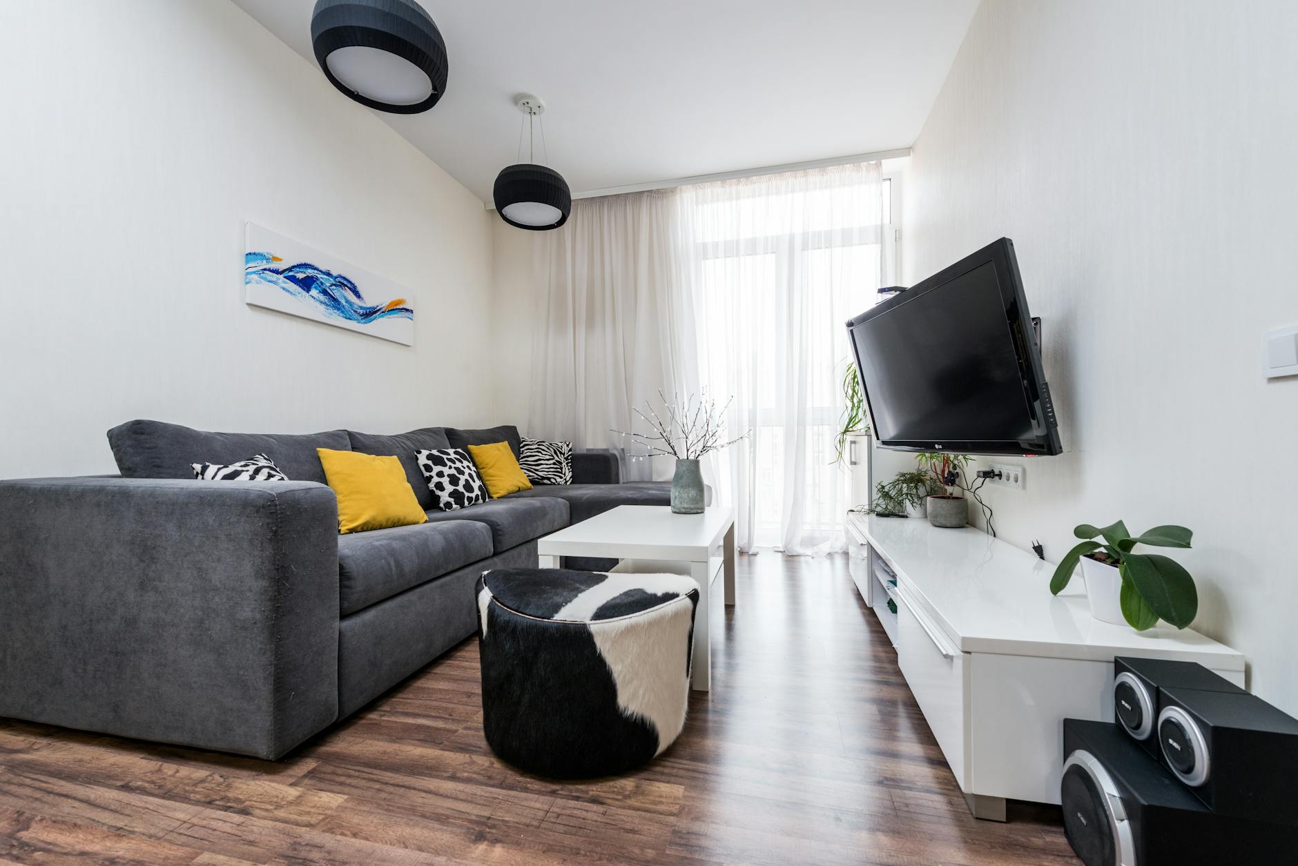 Jasny minimalistyczny salon z szarą sofą i żółtymi poduszkami