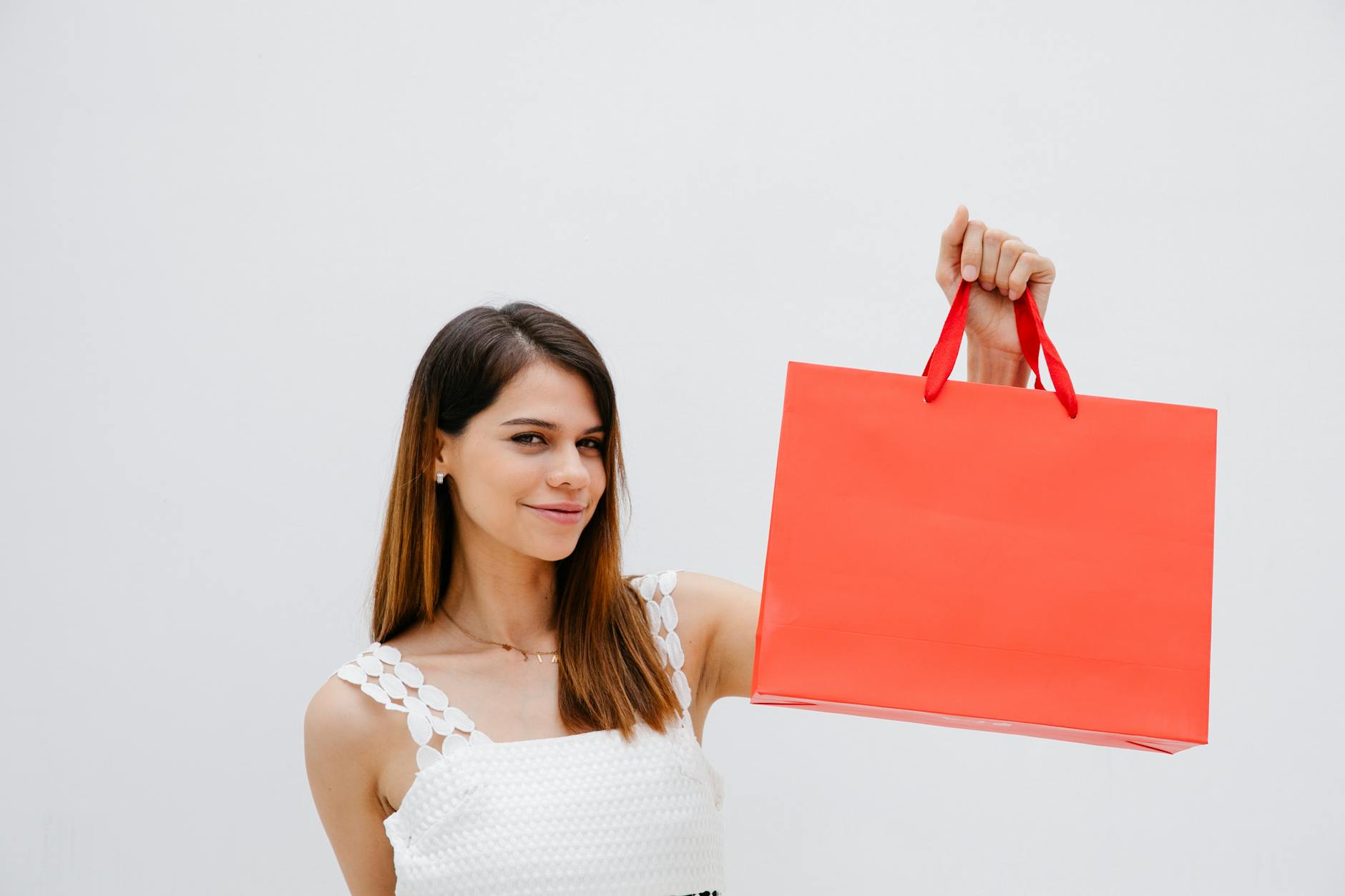 Kobieta z czerwonym shopperem pozuje uśmiechnięta w studiu