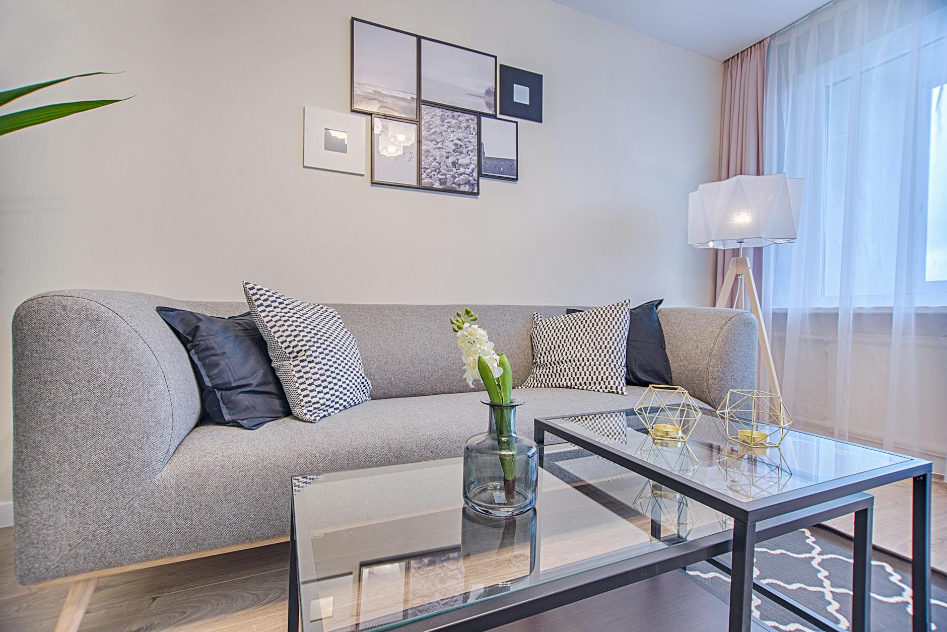 Minimalistyczny salon z szarą sofą, geometrycznymi dekoracjami i obrazami